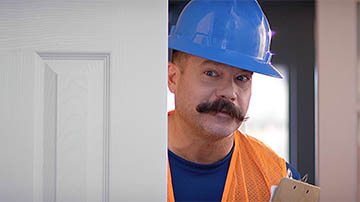 A construction worker peeks around a door