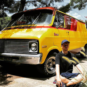 Rob Rigdon sitting in front of a sweet 70's van