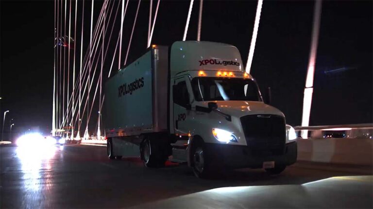 An image of a semi-truck crossing a bridge at night.